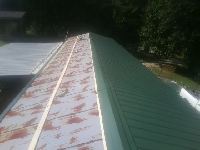 Old rusted panels beside newly installed green metal roofing — Wind Damage Roof Repair by Roofing Brothers in Hereford